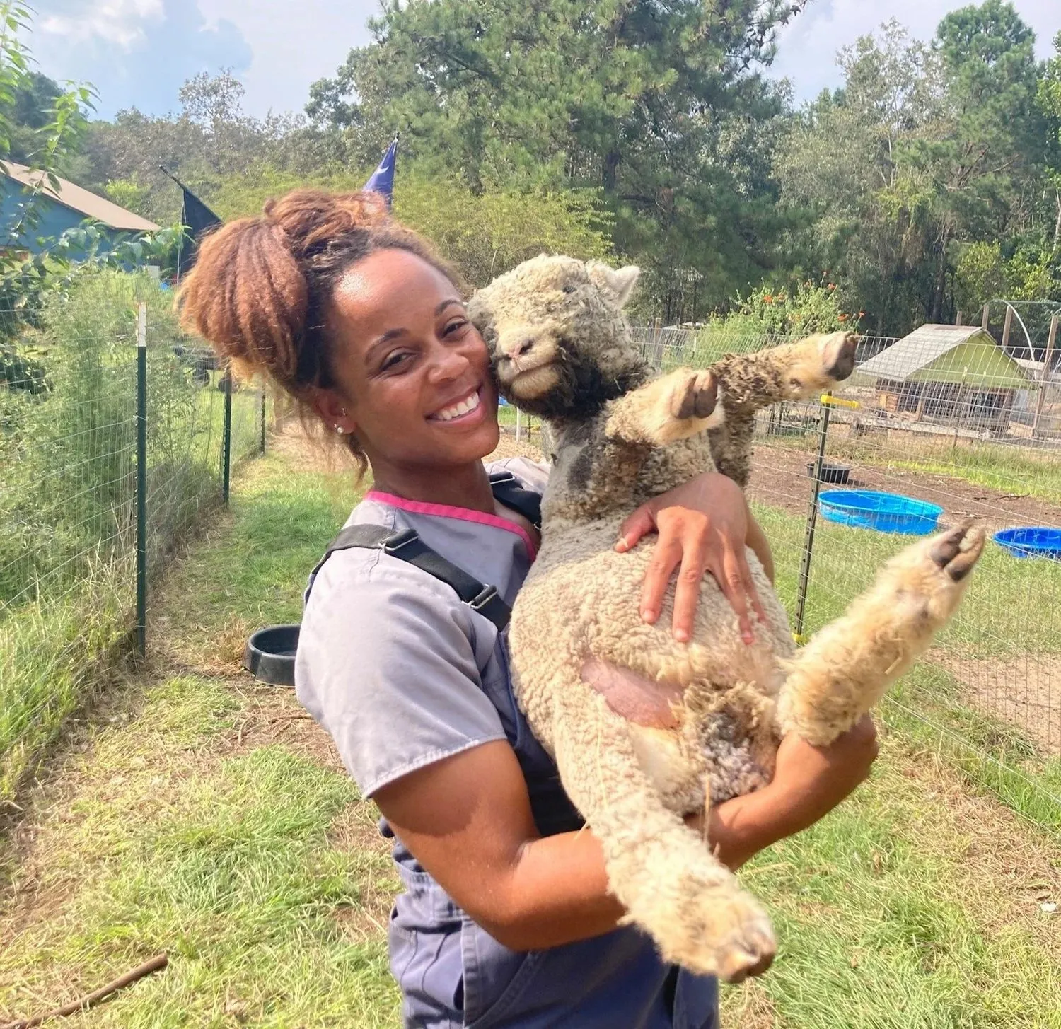 Ark team member smiling while holding a woolly sheep